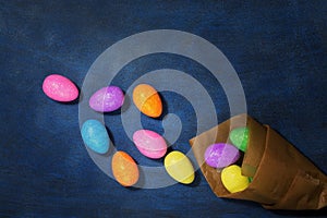Easter colored eggs in paper bag on a blue background. Top view, copy space