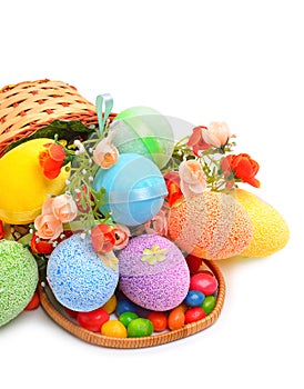 Easter colored plastic eggs, flowers and caramels in the basket