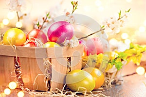 Easter colorful eggs in the basket. Beautiful colorful yellow, pink and orange color eggs with decorations and spring flowers