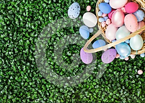 Easter colorful eggs in a basket on the green grass. Beautiful Easter composition. Copy space. View from above