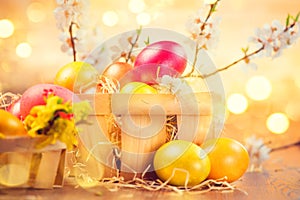 Easter colorful eggs in the basket and spring flowers over bright blurred background