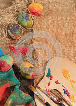 Easter colorful eggs with two painter's brushes,a wooden palette and a hand painted cloth.
