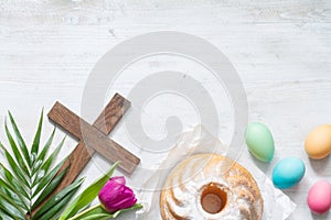 Easter colorful spring tulips with palm cross cake and eggs decoration on white wooden natural background