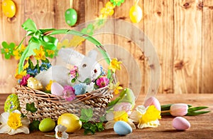 Easter composition with bunny in basket, spring flowers and colorful Easter eggs
