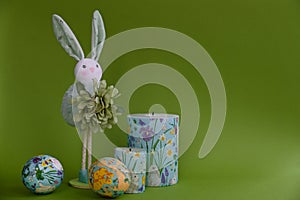 Easter composition with bunny ,Easter eggs and candles on a green background.