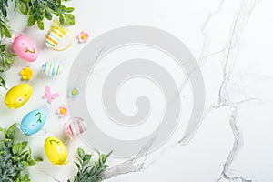 Easter composition with colored eggs and green plants on white background.