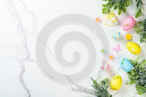 Easter composition with colored eggs and green plants on white background.