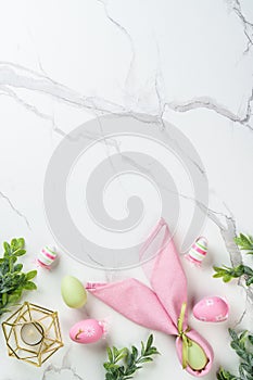 Easter composition with colored eggs and green plants on white background.