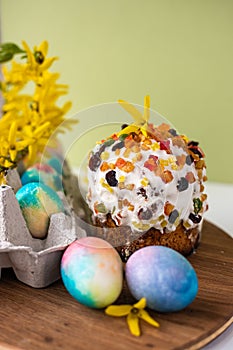 Easter composition with colorful eggs, wooden stand and spring flowers on a yellow background. Easter cake Banner. copy