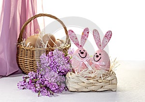 Easter composition with eggs in a wicker basket, funny toys and field flowers