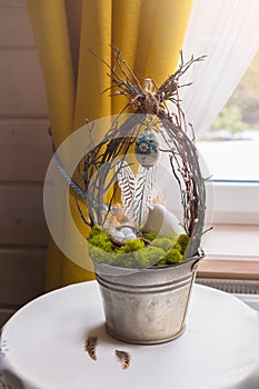 Easter composition with feathers, bird, nest, eggs, natural moss in iron pot, selective focus