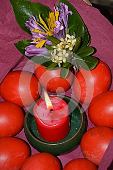 Easter composition with flowers, a candle and the painted eggs. Red prevails. Bright, juicy and festive