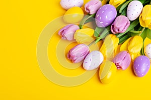 Easter composition. Multicolored easter eggs and tulips on yellow background. Easter concept. Copy space