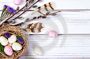Easter composition with a nest, eggs and branches on wooden table.