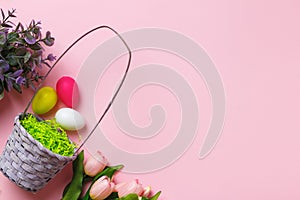 Easter composition on a pink background. Basket of eggs flowers tulips. Flat lay copy space top view
