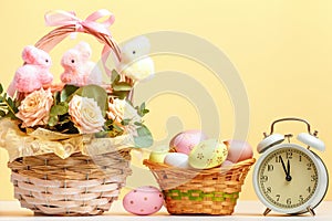 Easter composition still life. Baskets with roses and eggs alarm clock on the table