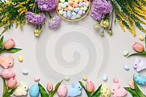 Easter composition. Top view frame of eggs in basket purple yellow flowers on gray background