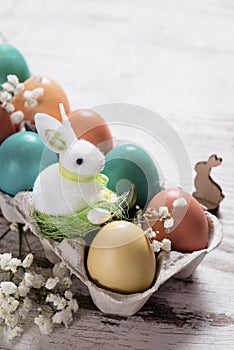 Easter concept with a bunny in nest. Painted easter eggs in egg