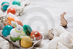 Easter concept with a bunny in nest. Painted easter eggs in egg