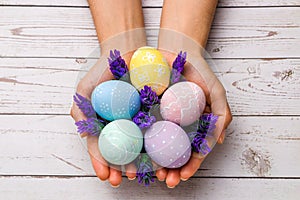 Easter concept. closeup beautiful woman hands holding hand-painted easter eggs in tender pastel colors and lavender flowers over