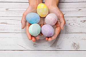 Easter concept. closeup beautiful woman hands holding hand-painted easter eggs in tender pastel colors over wooden table