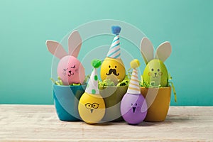 Easter concept with cute handmade eggs in coffee cups, bunny, chicks and party hats