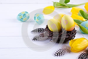 Easter concept - Decorative willow nest with decorative eggs, feather on white background. Copyspace for text.