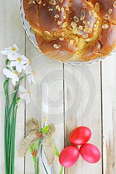 Easter concept with easter candle, red eggs, tsoureki and flowers