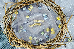 Easter concept. Easter egg shaped candies, Happy Easter letters in a wicker wreath on a cotton dotted tablecloth