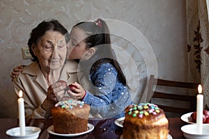 Easter concept. Grandmother with granddaughter are holding Easter eggs at home