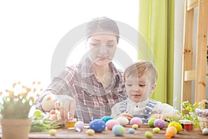 Easter concept. Happy mother and her cute child getting ready for Easter by painting the eggs. Happy family Mom and children son