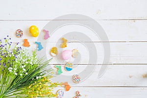 Easter cookies, bunnies and eggs with flowers on white wooden table