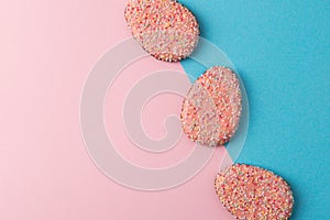 Easter cookies in a shape of eggs on blue and pink background Easter minimalist concept top view