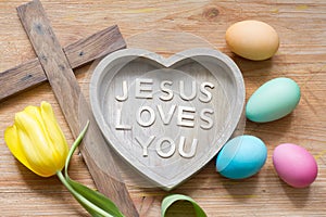 Easter cross and heart with inscription Jesus loves you on abstract wooden spring board