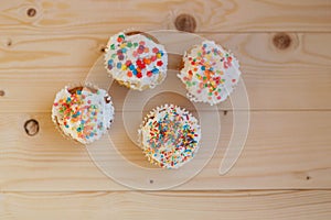 Easter cupcakes with cream and small confetti on a wooden table.