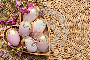 Easter decor. Easter eggs painted in gold in a heart-shaped wooden bowl