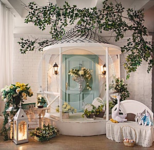 Easter decor for a photo studio for children's shootings. White gazebo with white bench decorated with flowers