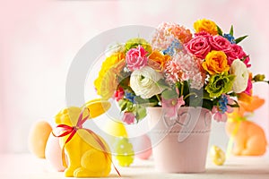 Easter decoration with beautiful spring flowers in vase, Easter eggs and bunny on white wooden table. Easter concept