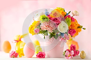 Easter decoration with beautiful spring flowers in vase, Easter eggs and bunny on white wooden table. Easter concept