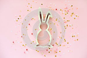 Easter decoration with bunny and confetti on pink background.