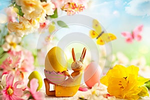 Easter decoration with bunny, Easter eggs and beautiful spring flowers on a blurred light background. Easter concept with copy