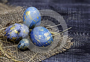 Easter decoration concept: blue painted eggs on the sackcloth with hay close-up