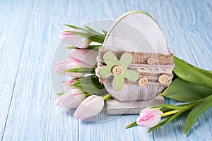 Easter decoration with easter egg and pink tulips on blue wooden background