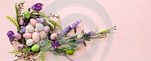 Easter decoration, egg nest on pink background. Festive flower wreath full of pastel color egg