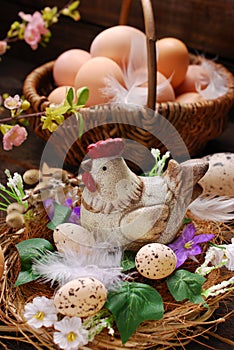 Easter decoration of hen in the nest and wicker basket with eggs