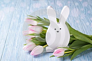 Easter decoration with rabbit and pink tulips on blue wooden background