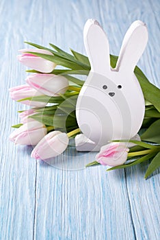 Easter decoration with rabbit and pink tulips on blue wooden background