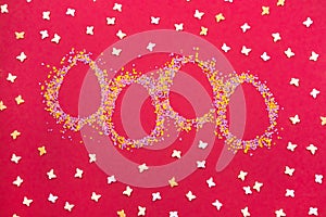 Easter decoration in the shape of easter eggs and color sugar sprinkle and butterflies on red background.