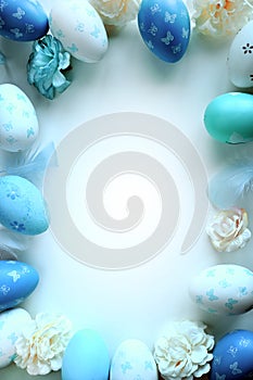 Easter decorations concept. Top view photo of colorful easter eggs and blue feathers on isolated pastel blue background.