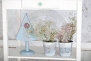 Easter decorations with spring white flowers in pots and a decorative blue birdhouse on table. Bouquet Gypsophila. Easter home dec